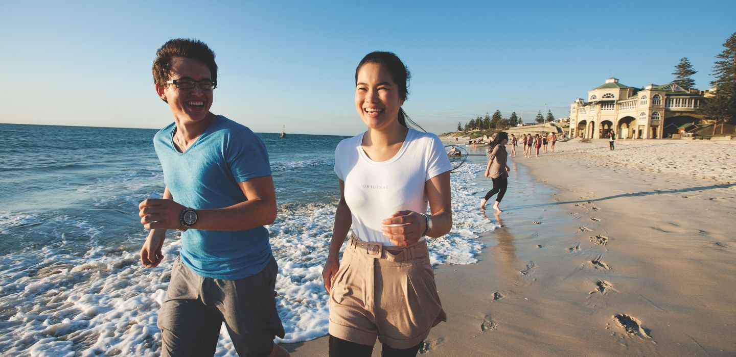 Off campus female and male walking on beach