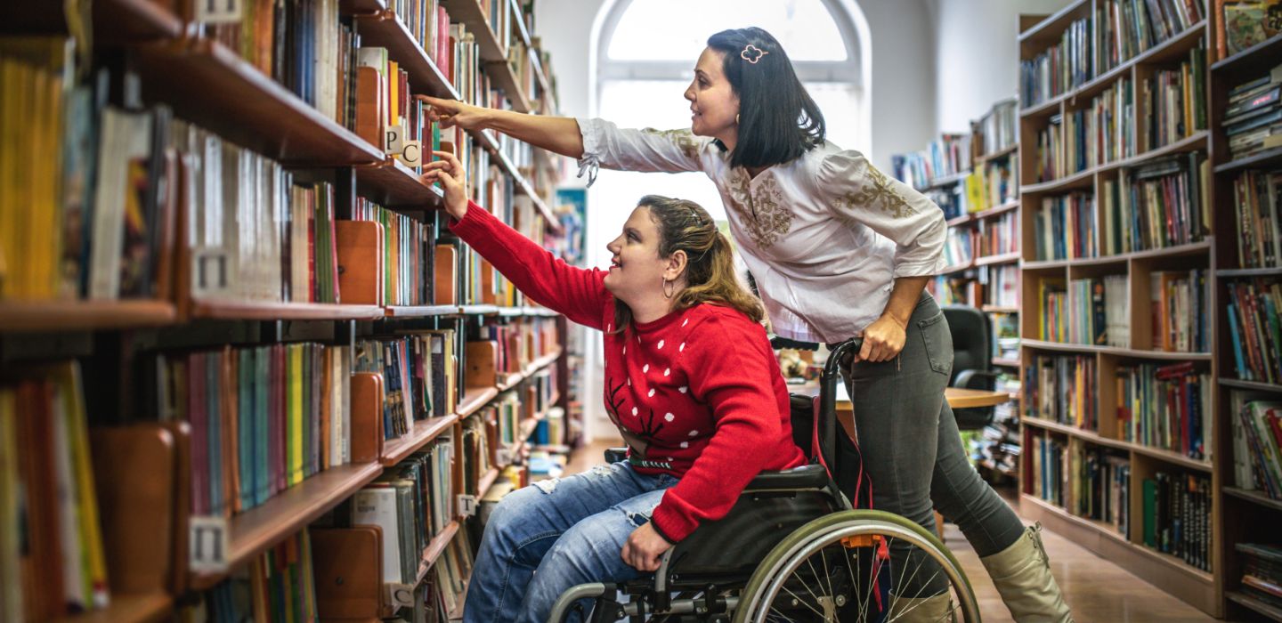 Off campus female on wheelchair reaching for books